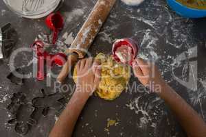 Cropped hand of boy putting flour on dough