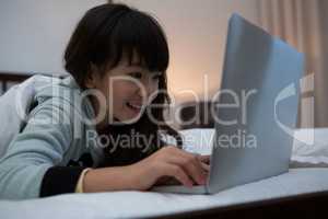 Smiling girl using laptop on bed