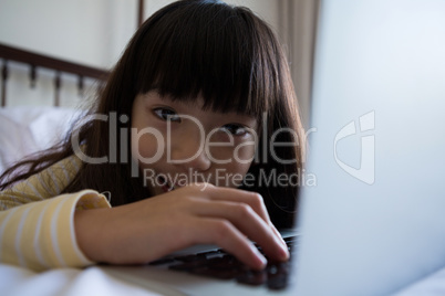 Portrait of girl using laptop on bed at home