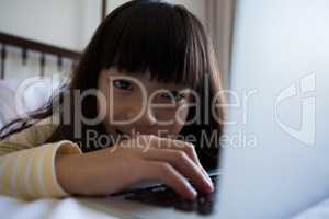 Portrait of girl using laptop on bed at home