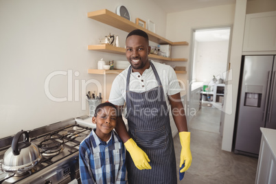 Smiling father and son standing together in kitchen