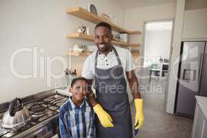 Smiling father and son standing together in kitchen