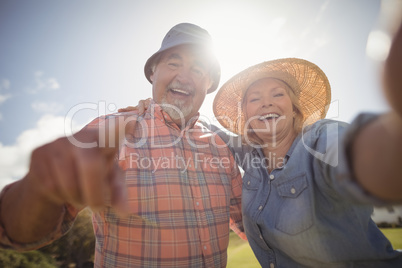 Smiling senior couple standing in lawn on a sunny day