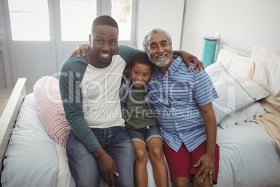 Smiling multi-generation family sitting together on bed