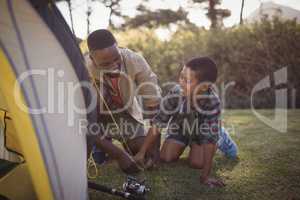 Father and son are setting up tent in park