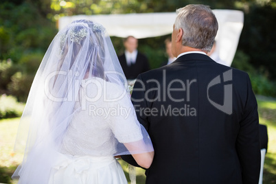 Bride standing with her father in park