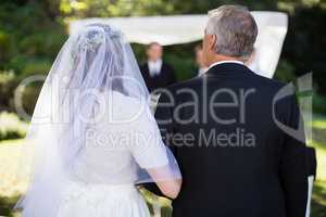 Bride standing with her father in park