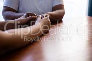 Cropped hands of nurse consoling senior woman at table