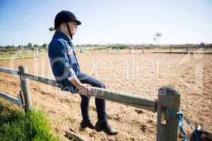 Girl sitting on wooden fence in the ranch