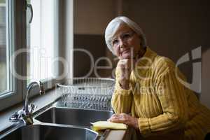 Smiling senior woman standing near kitchen worktop