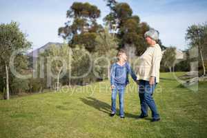 Smiling granddaughter and grandmother standing together in garden