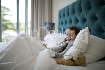Girl using mobile phone on bed in bedroom