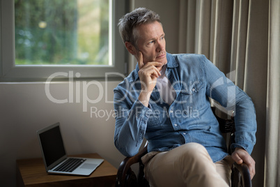 Thoughtful man sitting on chair in living room