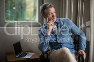 Thoughtful man sitting on chair in living room