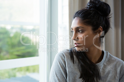 Thoughtful young woman by window