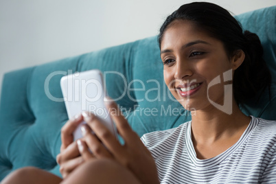 Smiling woman using phone in bedroom