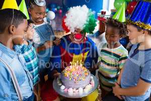 High angle view of children with clown standing by cake
