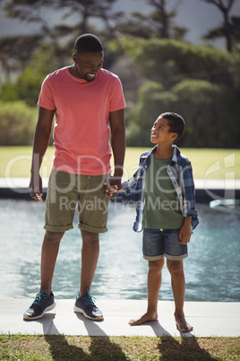 Father and son interacting while holding hands near poolside