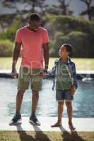 Father and son interacting while holding hands near poolside