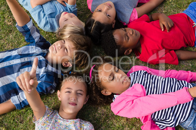 Overhead view of children with arms raised lying on field