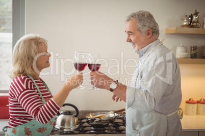 Senior couple toasting glasses of wine while preparing food