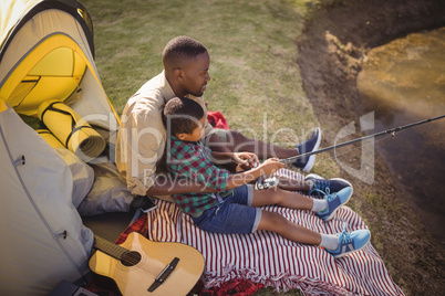 Father and son fishing together in park