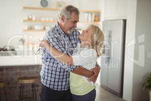 Smiling senior couple embracing each other in kitchen
