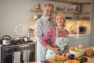 Smiling senior couple embracing each other in kitchen