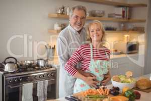 Smiling senior couple embracing each other in kitchen