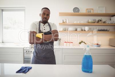 Confident man standing with arms crossed in kitchen