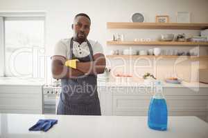 Confident man standing with arms crossed in kitchen