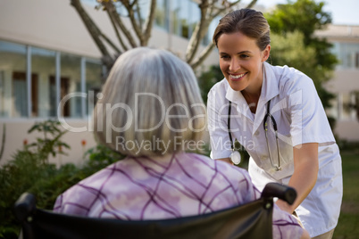 Doctor talking to senior woman sitting on wheelchair