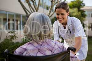 Doctor talking to senior woman sitting on wheelchair