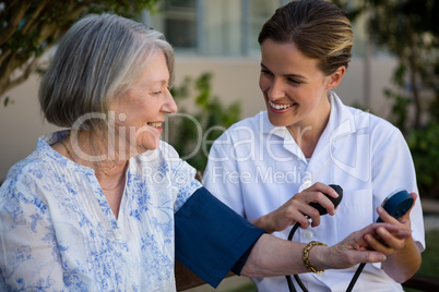 Female doctor examining senior woman in park