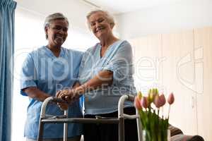 Nurse standing by senior woman holding walker in nursing home