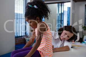Physiotherapist examining back of girl patient in clinic
