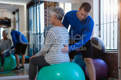 Physiotherapist assisting senior woman on exercise ball