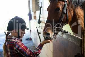 Girl feeding the horse in the stable