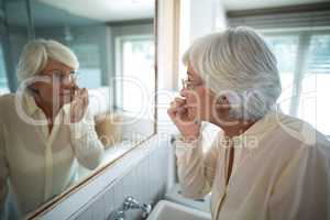 Senior woman checking her skin in mirror