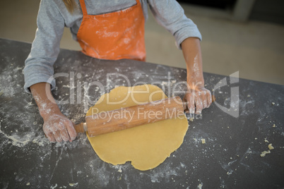 Little girl flattening dough on the kitchen counter