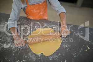 Little girl flattening dough on the kitchen counter