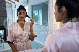 Woman applying blush with reflection on mirror