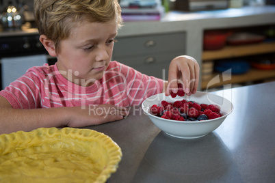 Boy having raspberries in kitchen