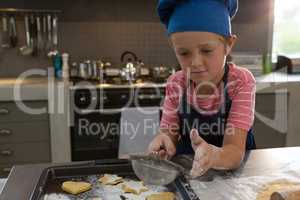Boy sprinkling flour on cookies