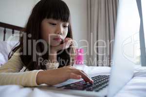 Girl using laptop while lying down on bed