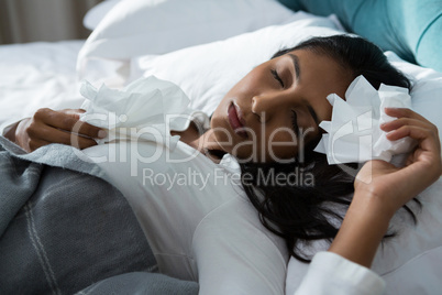 Sick woman with tissues sleeping on bed