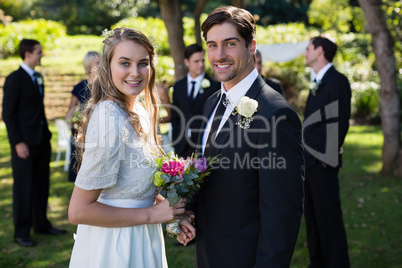 Happy bride and groom standing in park