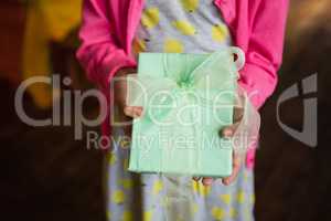 Birthday girl holding gift box at home