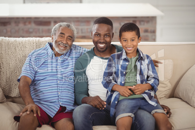 Smiling multi-generation family sitting together on sofa