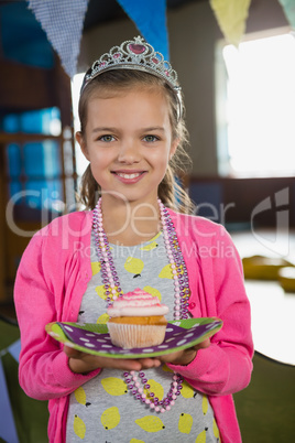 Birthday girl holding a cupcake at home